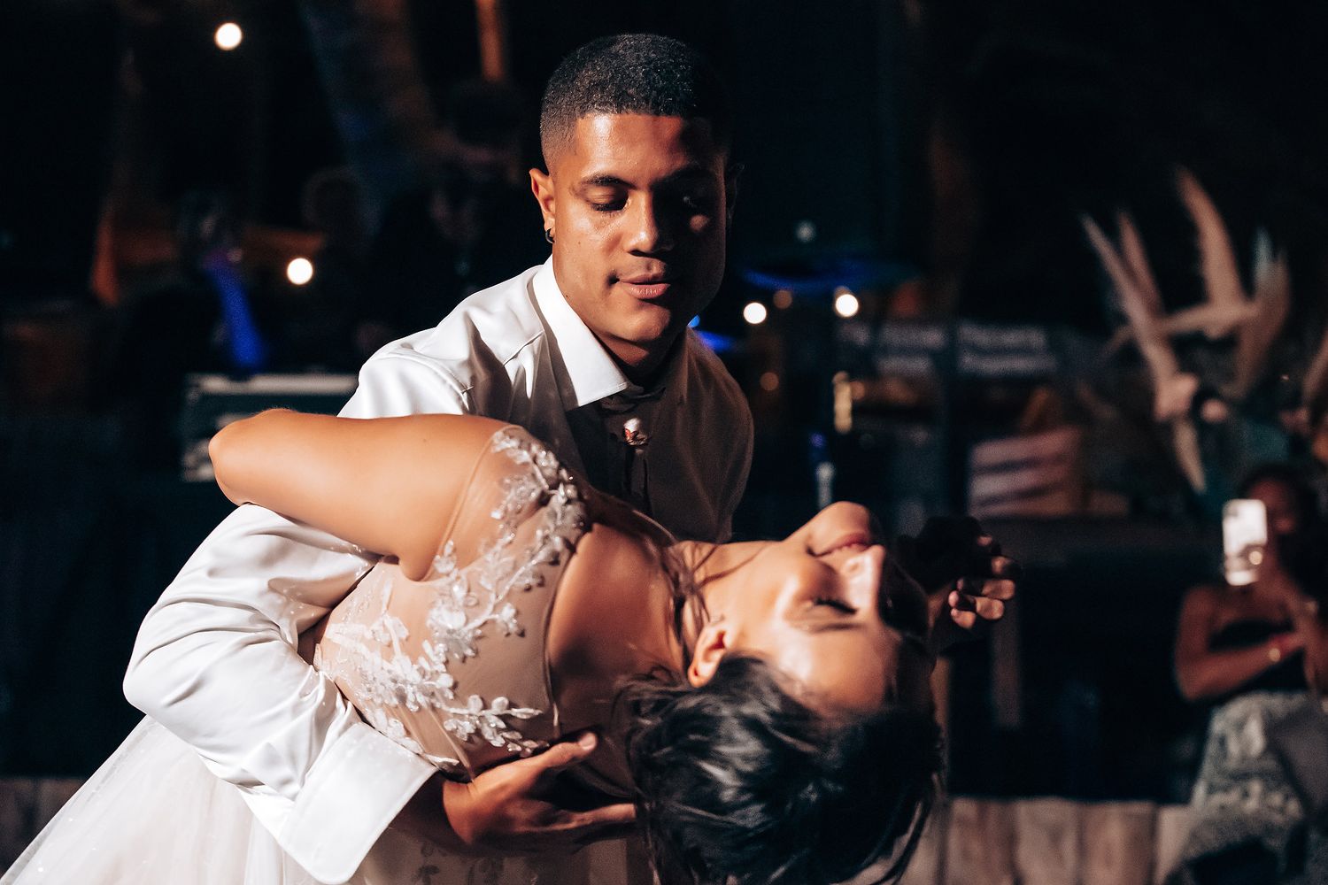 Romantic dance under twinkling lights at an outdoor evening wedding reception.