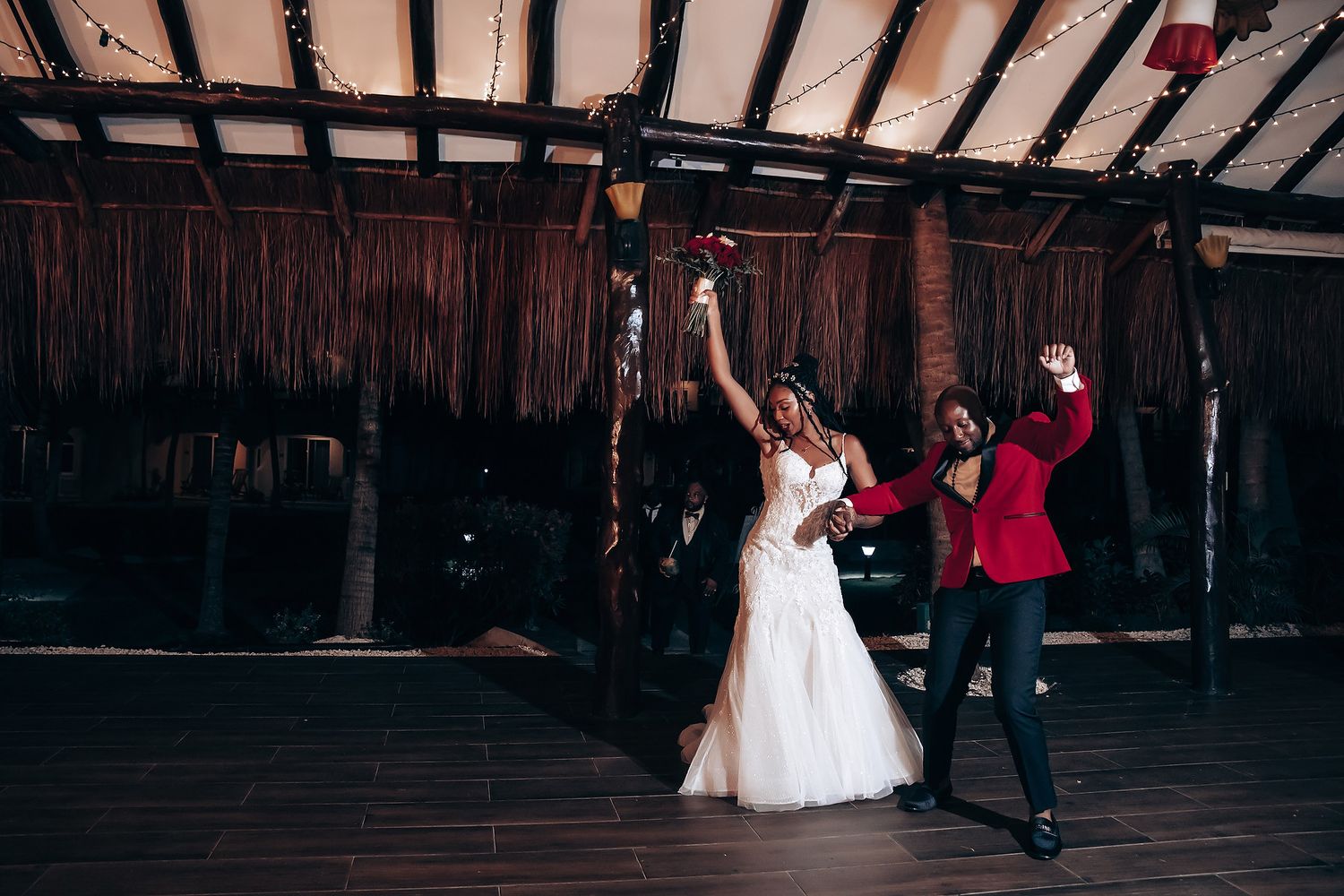 Dancers in formal attire move energetically on a rustic wooden dance floor under exposed beams.