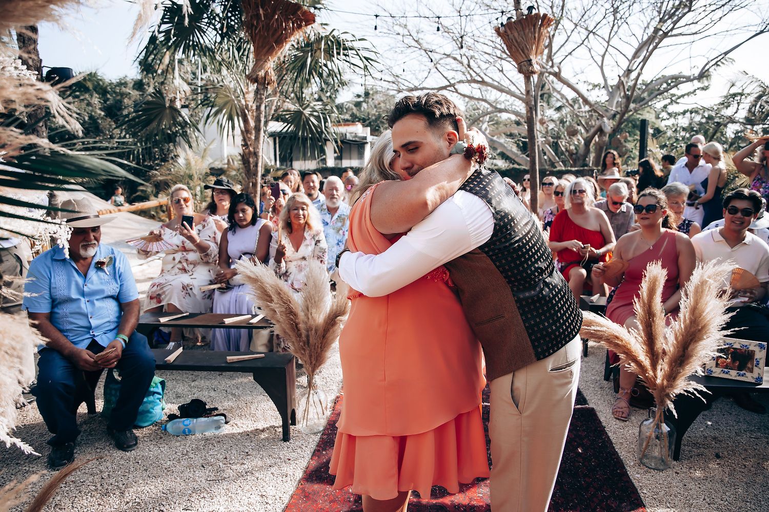 Guests dance and celebrate together at an outdoor wedding reception on a sunny day.