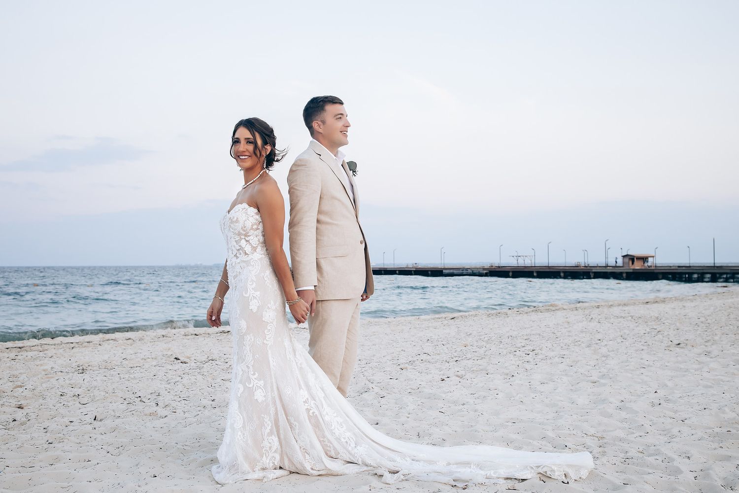Newlyweds walk along pristine white sand beach with ocean views.