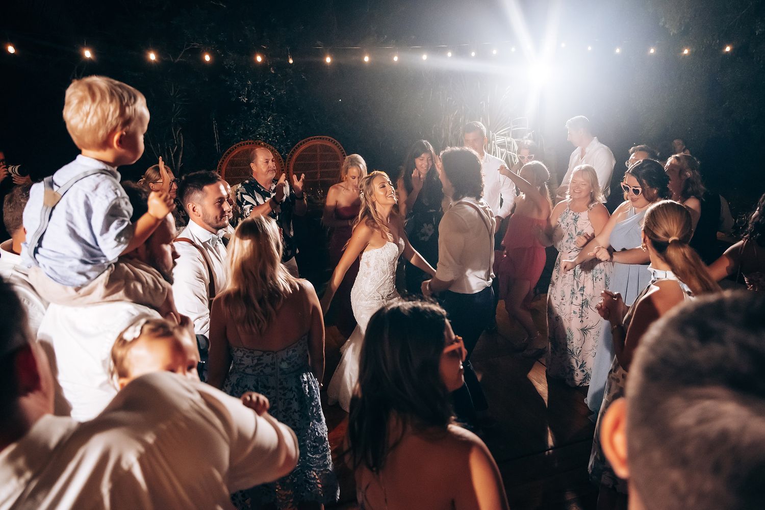 Couples dance together under dramatic lighting at a nighttime wedding reception.