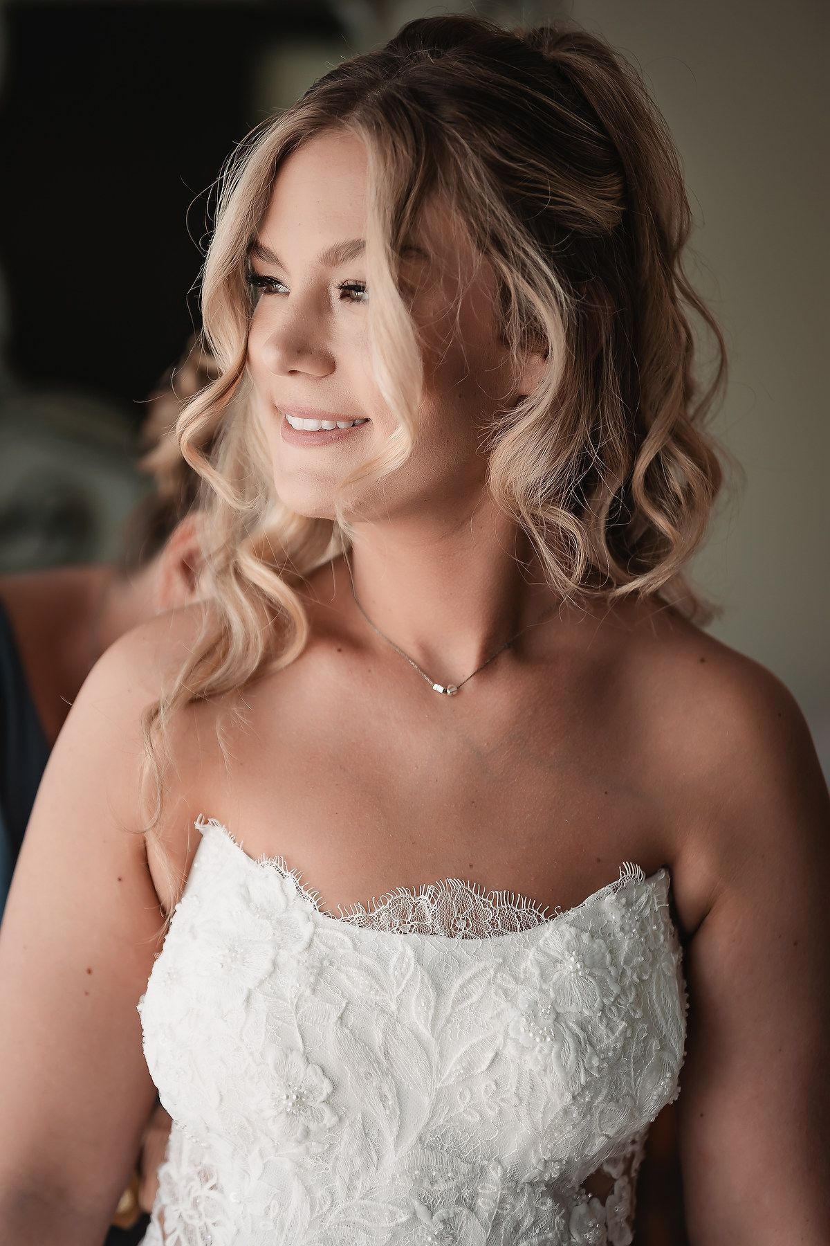 Bride wearing strapless lace wedding gown with delicate neckline detail.