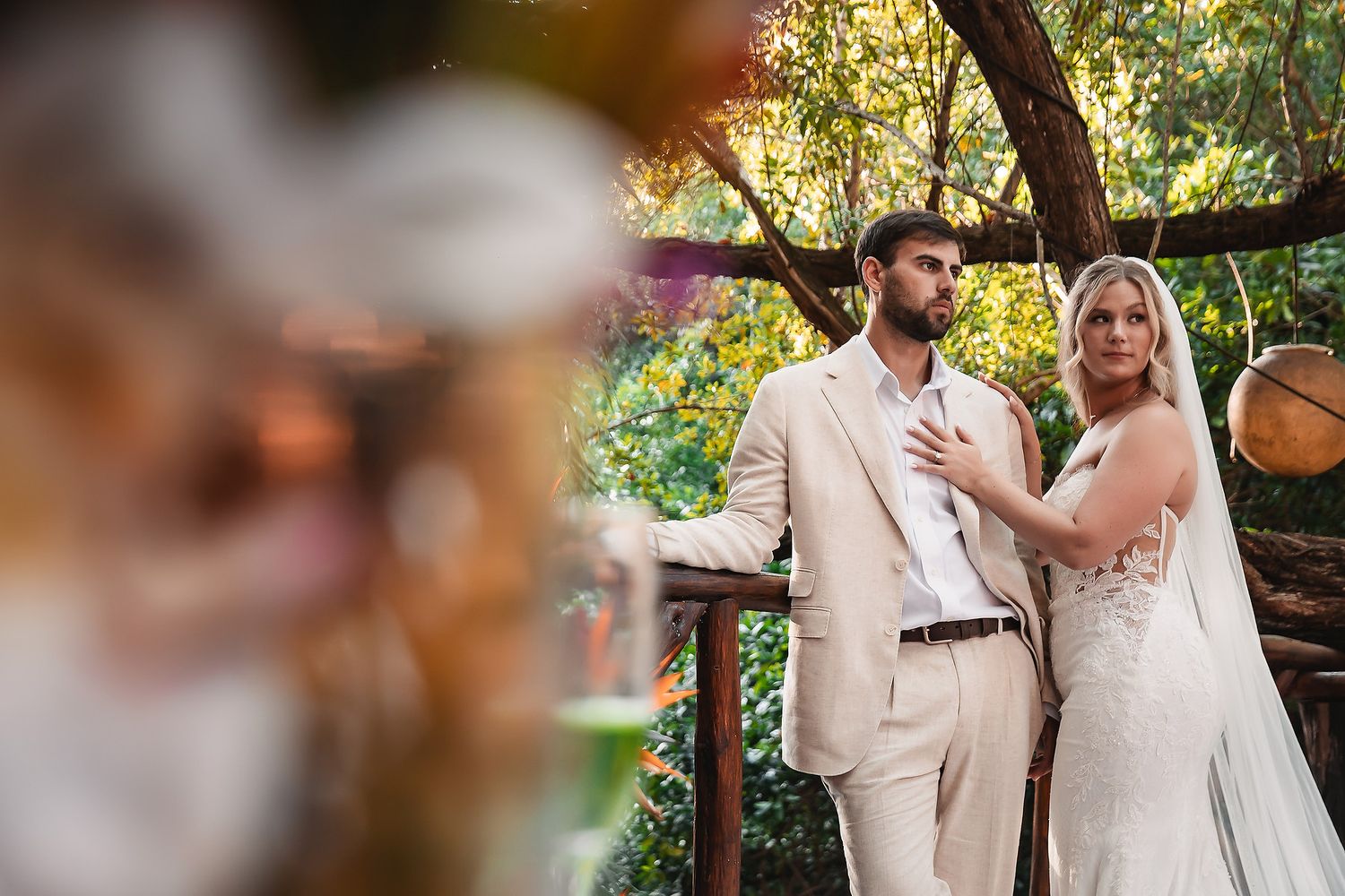 A wedding couple embraces in a lush garden setting with soft natural lighting.