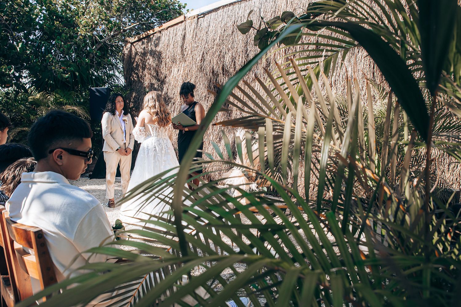 Tropical wedding venue with palm fronds and thatched roof details.