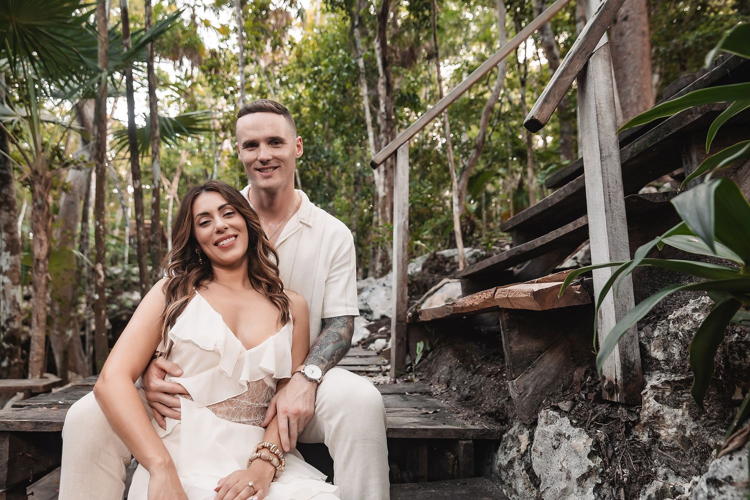 Intimate couple portrait session on weathered wooden walkway in tropical setting.