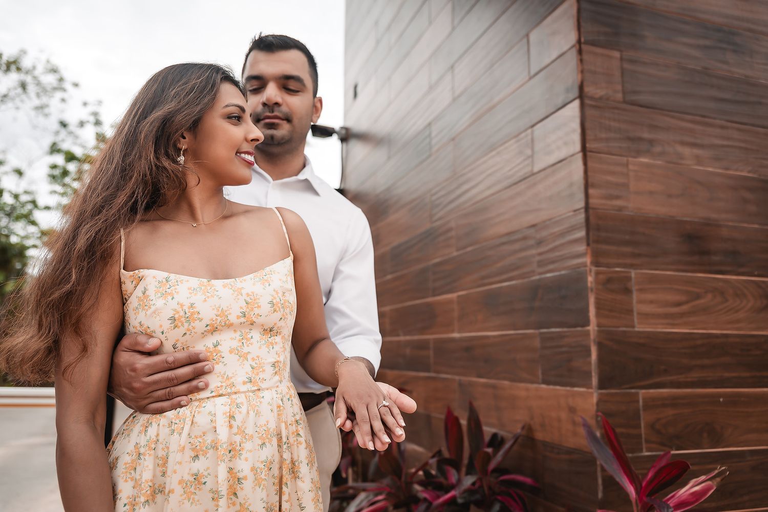 Couple sharing tender moments against a modern wooden wall exterior.