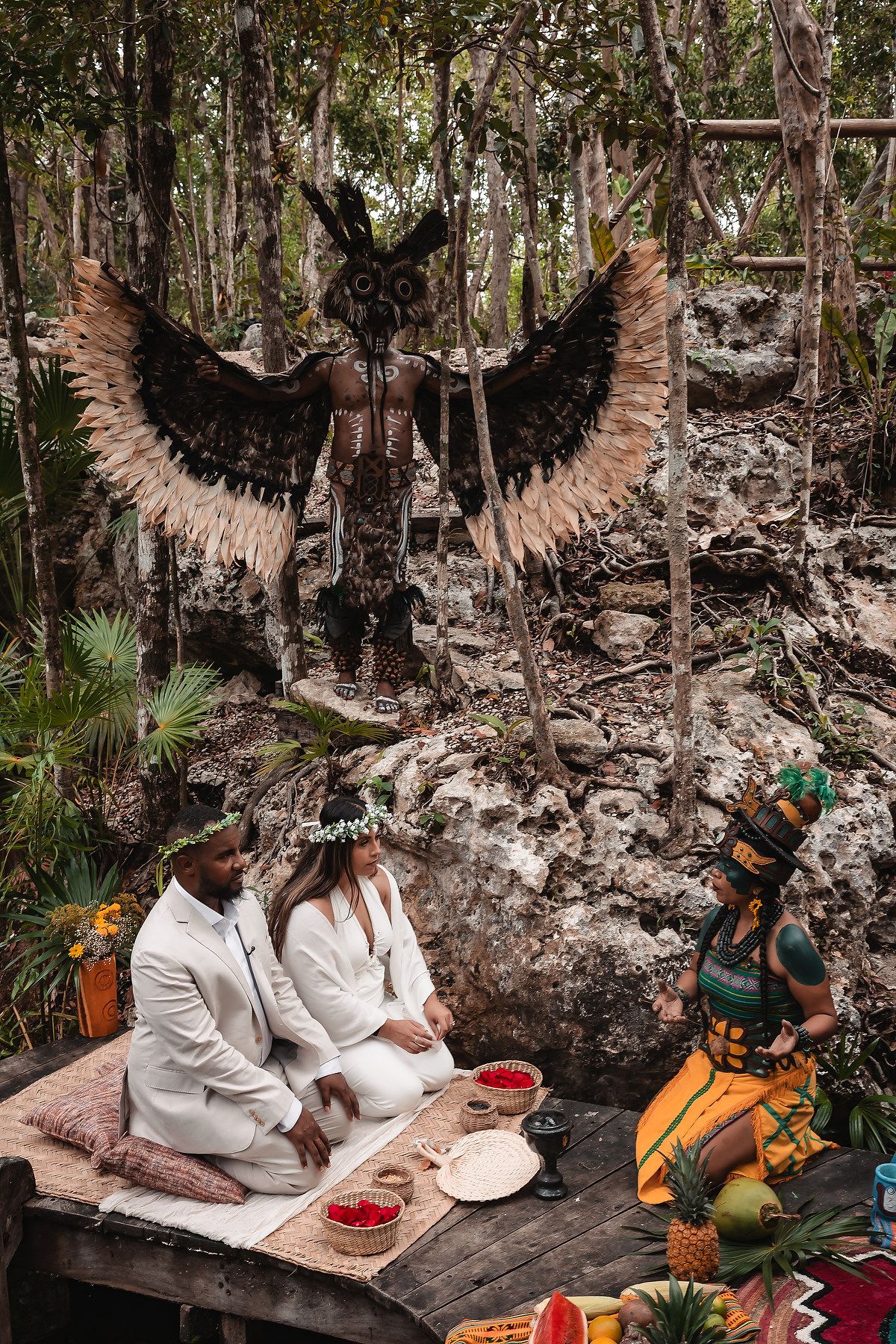 A Mayan ceremony with large feathered wings and traditional decorations in a jungle setting.