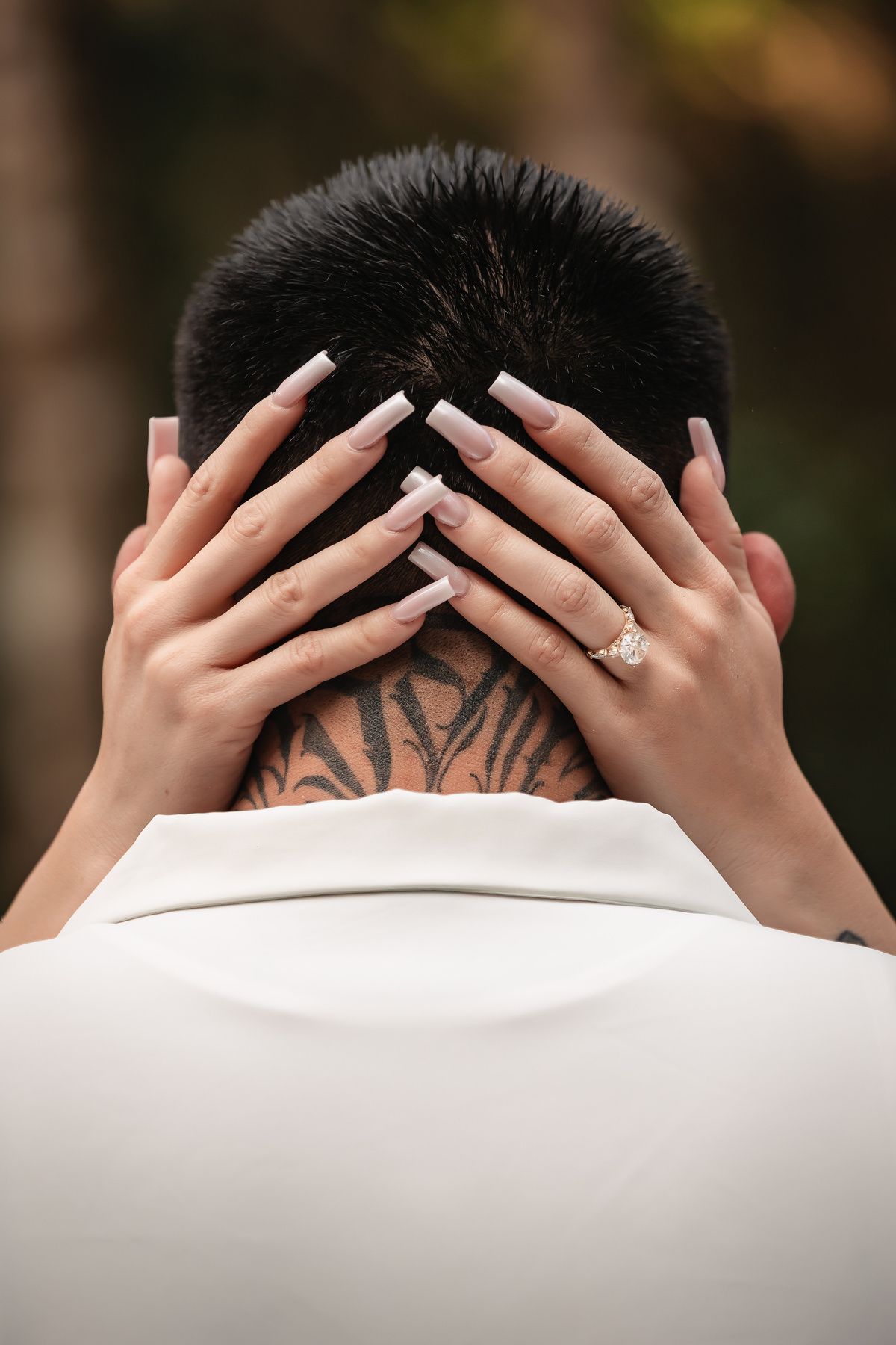 Close-up view of hands with rings and tattoos against white fabric background.