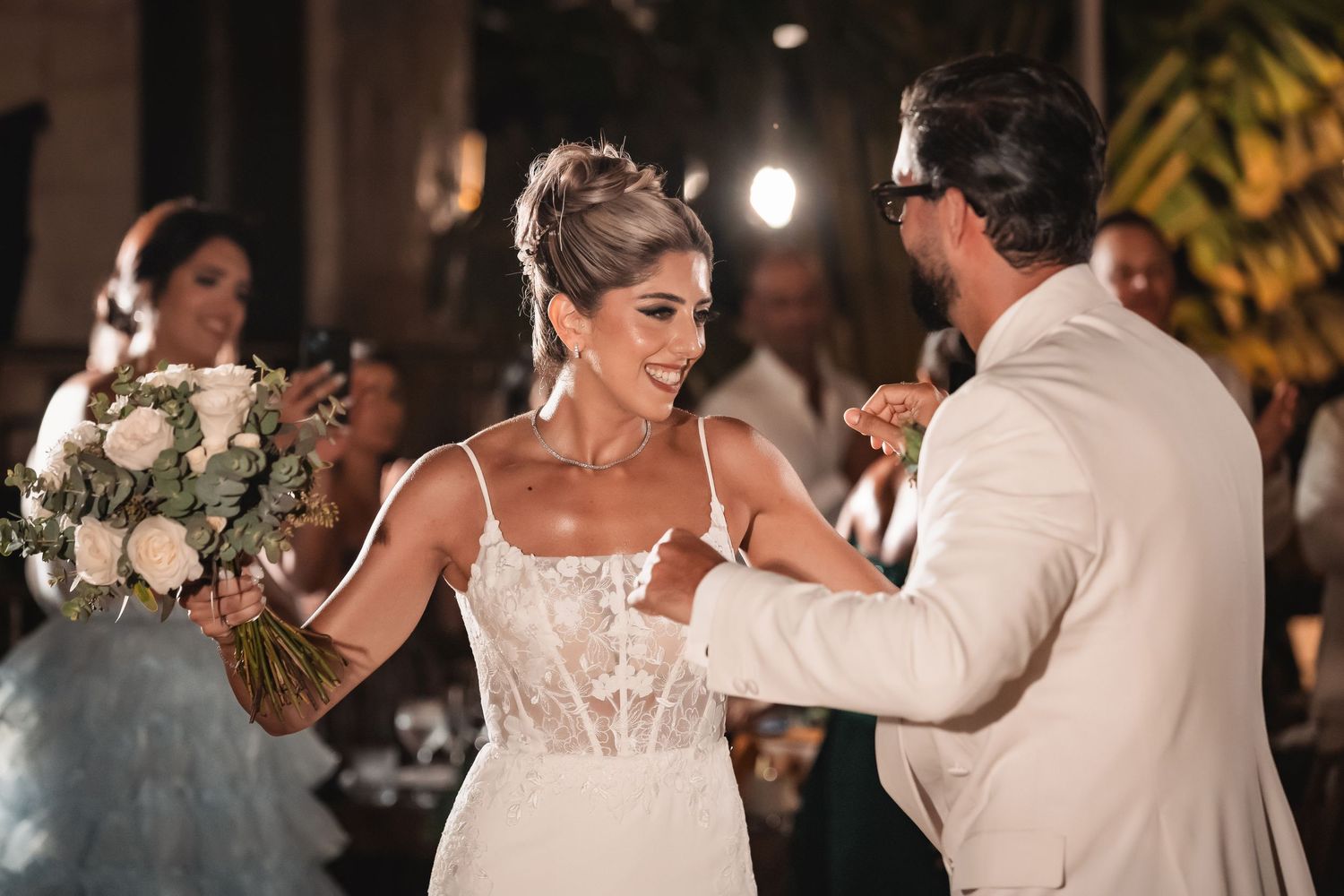 A joyful dance celebration at an outdoor wedding reception with string lights overhead.