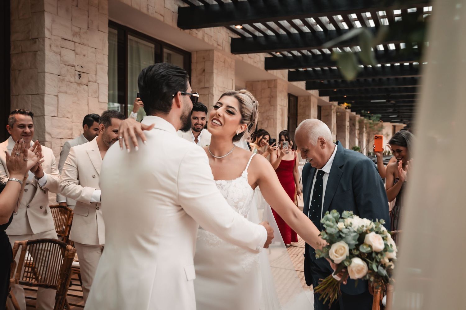 Wedding reception venue features elegant stone columns and wooden pergola overhead.