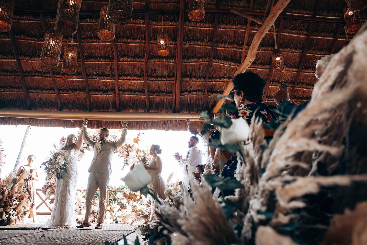 Interior view of a dimly lit thatched roof venue with hanging lanterns and natural light.