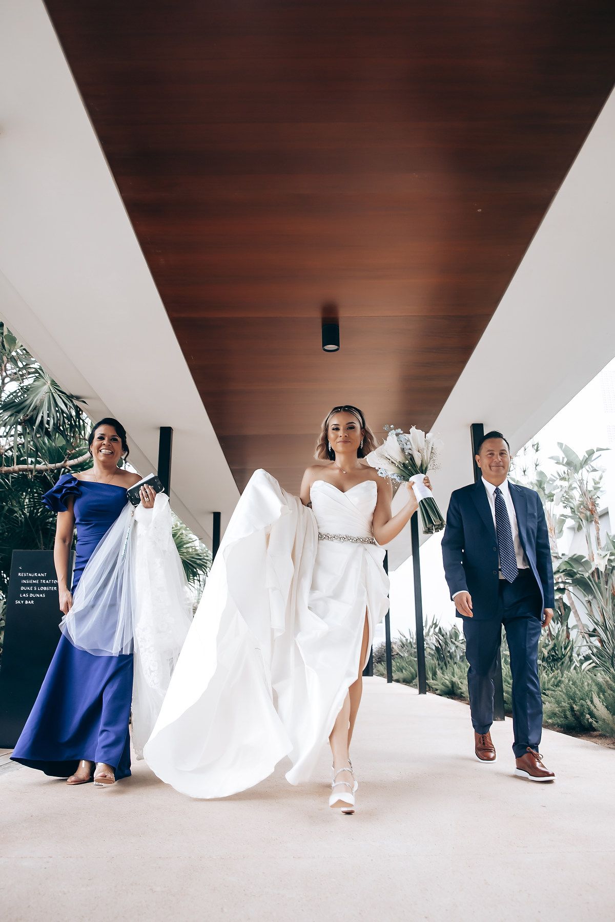 Creative wedding party photo under modern white architectural columns.
