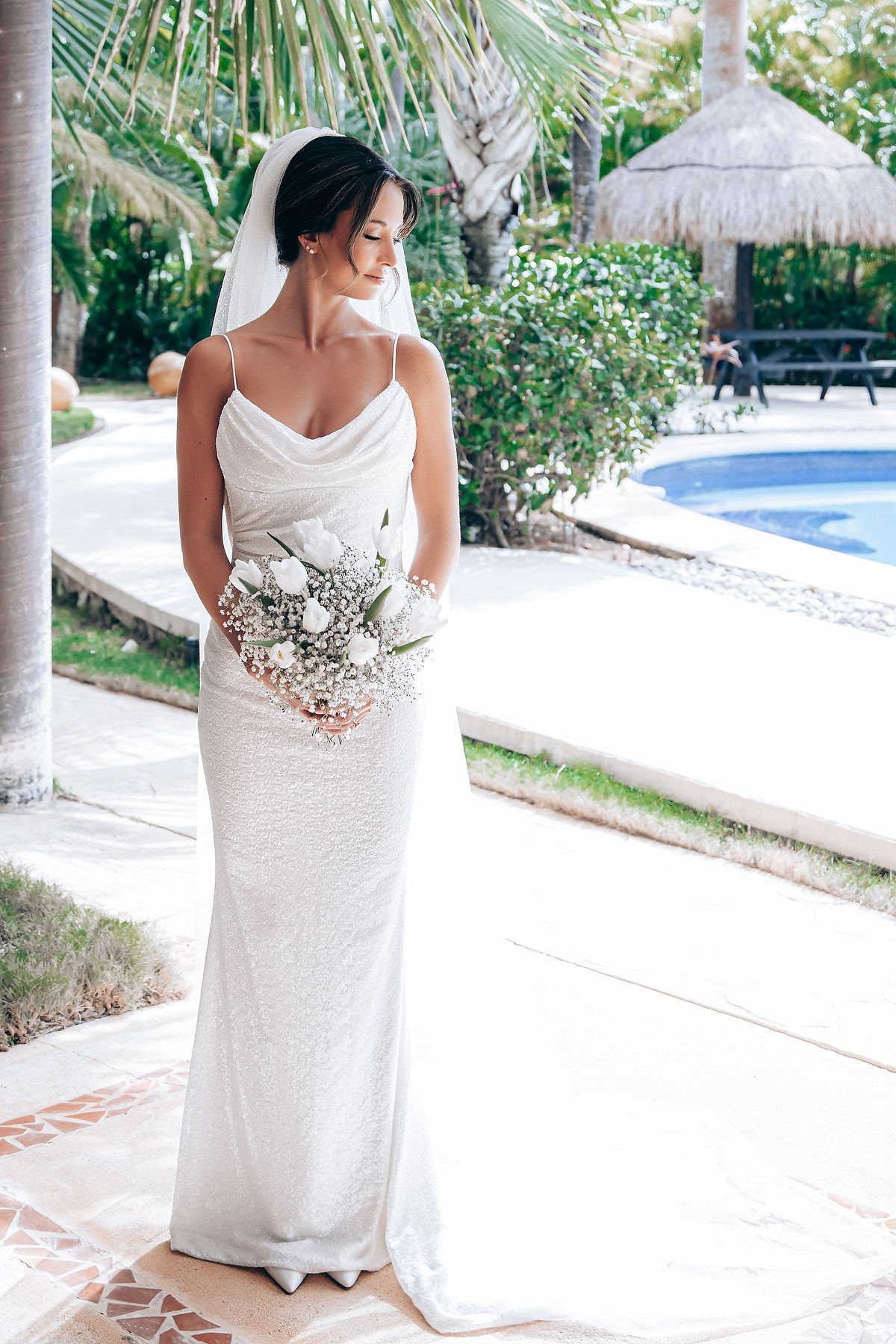 A white lace wedding dress displayed in multiple angles at a tropical resort setting with palm trees and pool views.