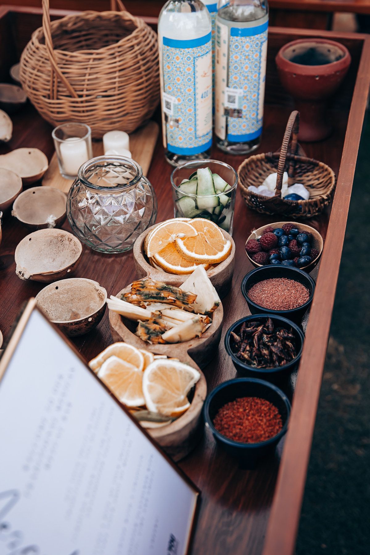 Close-up of drink garnishes and cocktail ingredients arranged on a wooden serving cart with citrus slices.