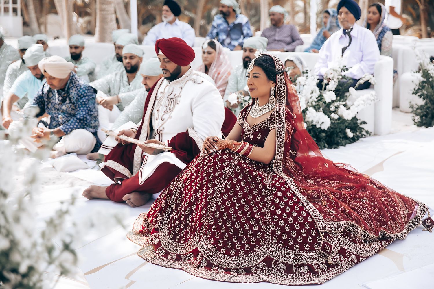 Wedding guests in traditional Indian attire seated during an outdoor ceremony.