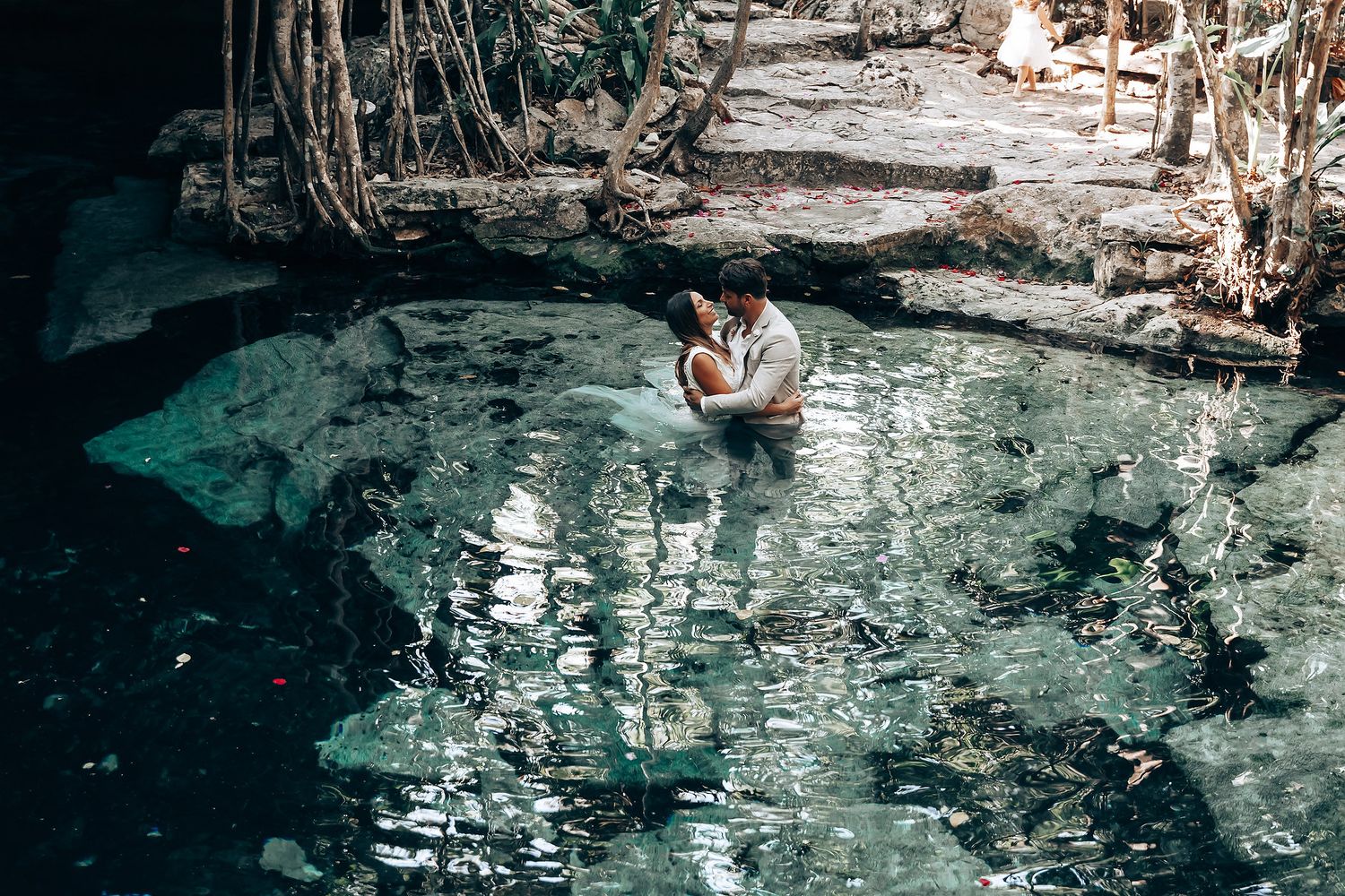 Romantic cenote photoshoot with turquoise water and dramatic rock formations.
