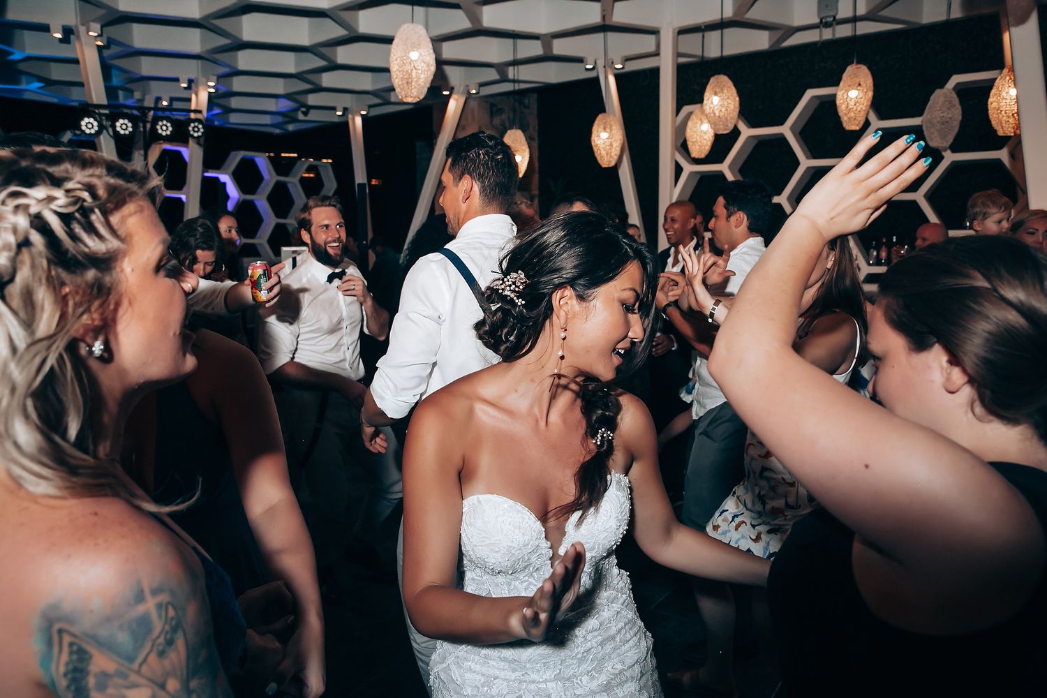 Lively dance party at a wedding reception with guests celebrating under modern lighting.