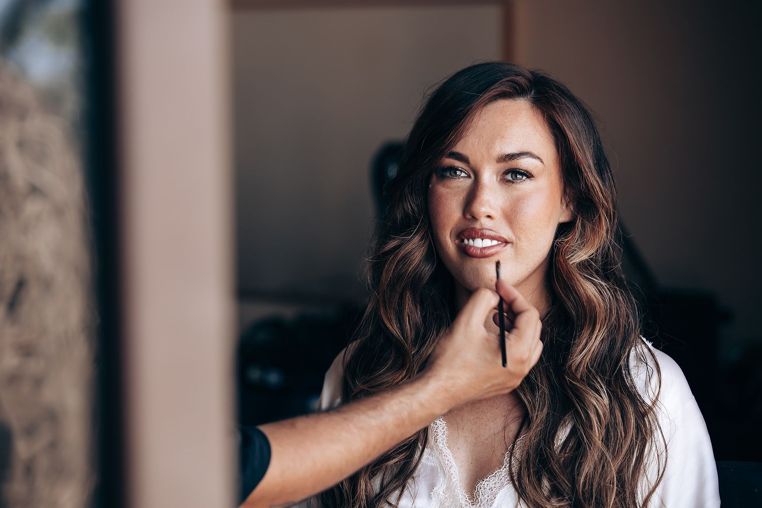 A professional photo series showing a woman with long brown hair laughing and posing against a dark background.