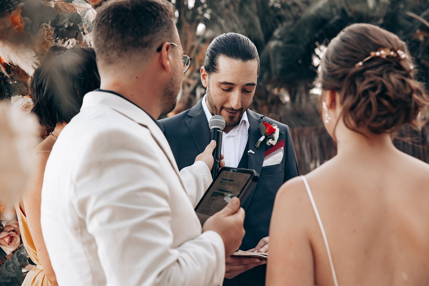 Wedding ceremony moments captured on a tropical beach with warm orange floral decorations.