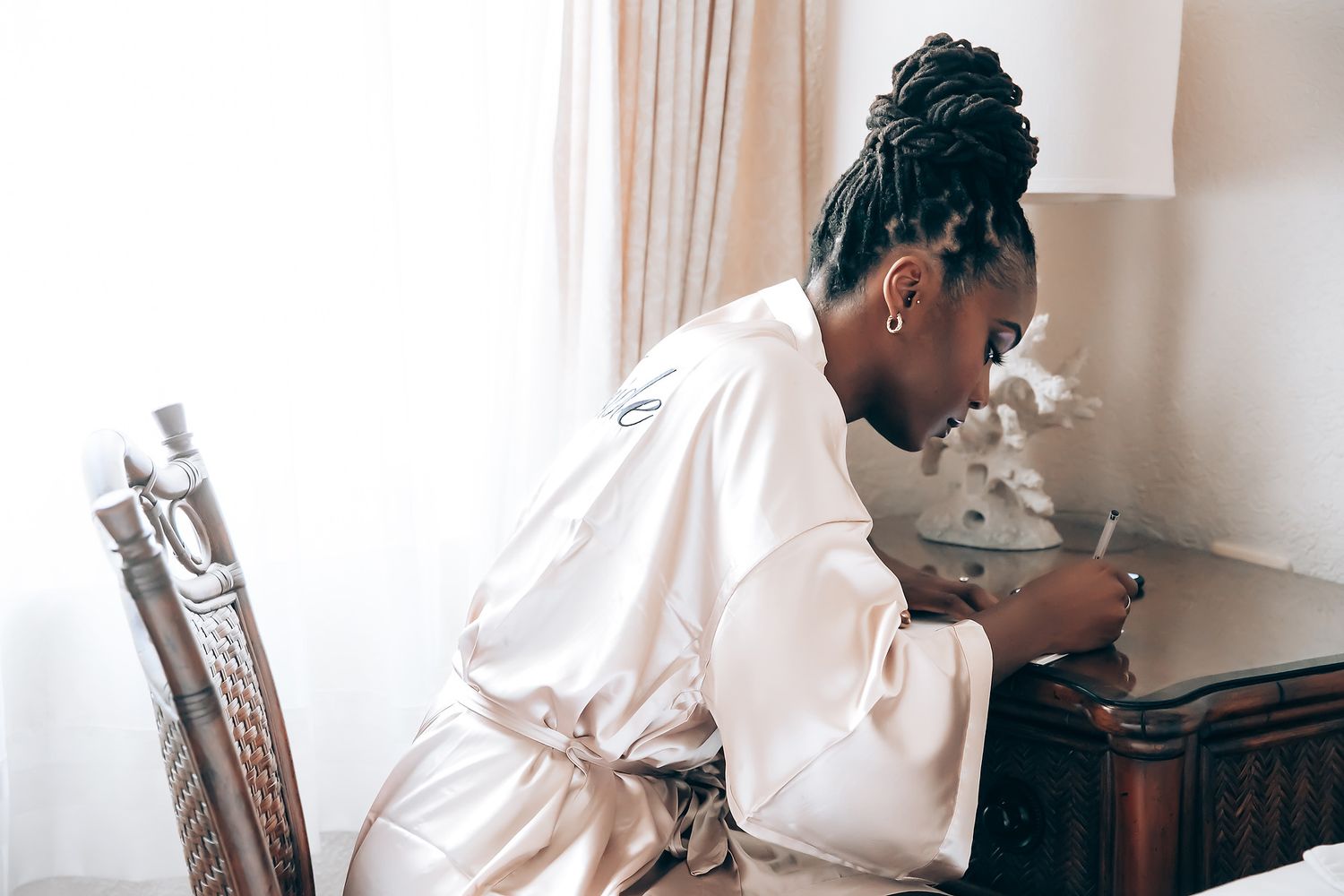 A wedding preparation scene showing someone getting their hair styled in a white robe.