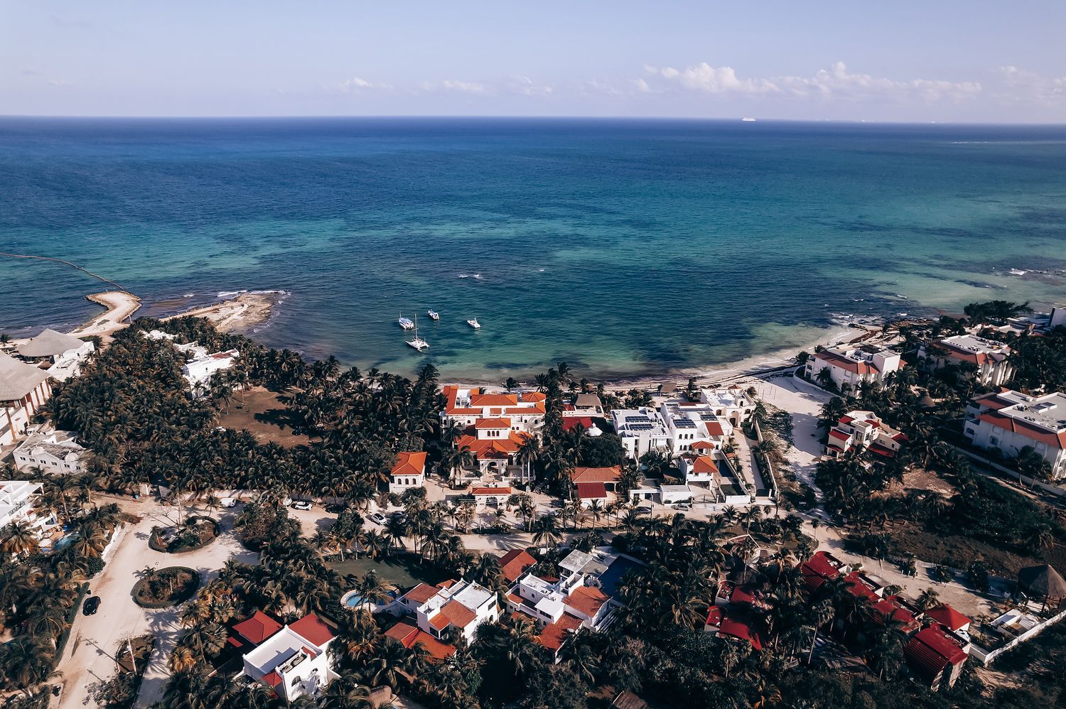 Aerial view of a coastal town with red-roofed buildings and turquoise waters.