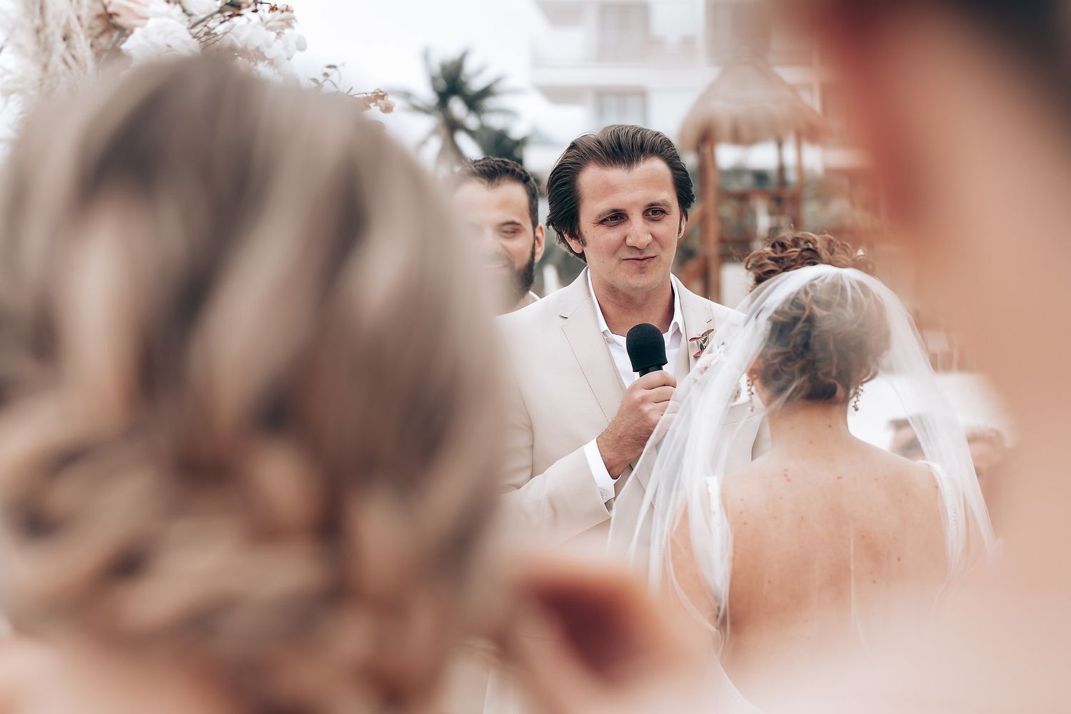 Intimate beachside wedding ceremony with palm trees swaying in the background.
