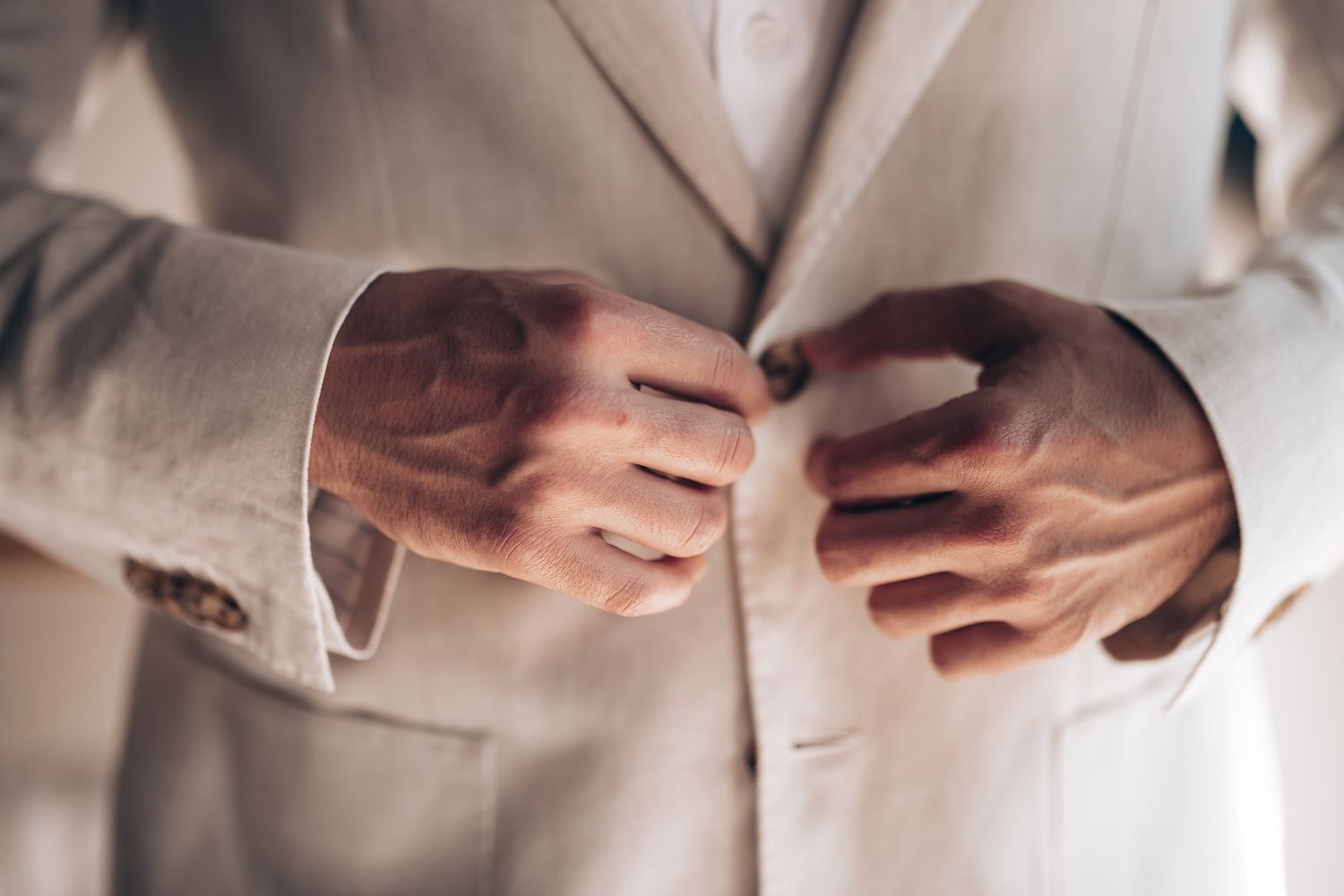 Close-up detail of hands adjusting buttons on formal attire.