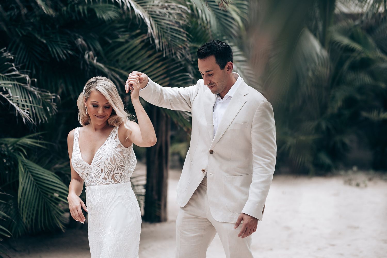 Wedding couple dancing and laughing together on sandy beach.