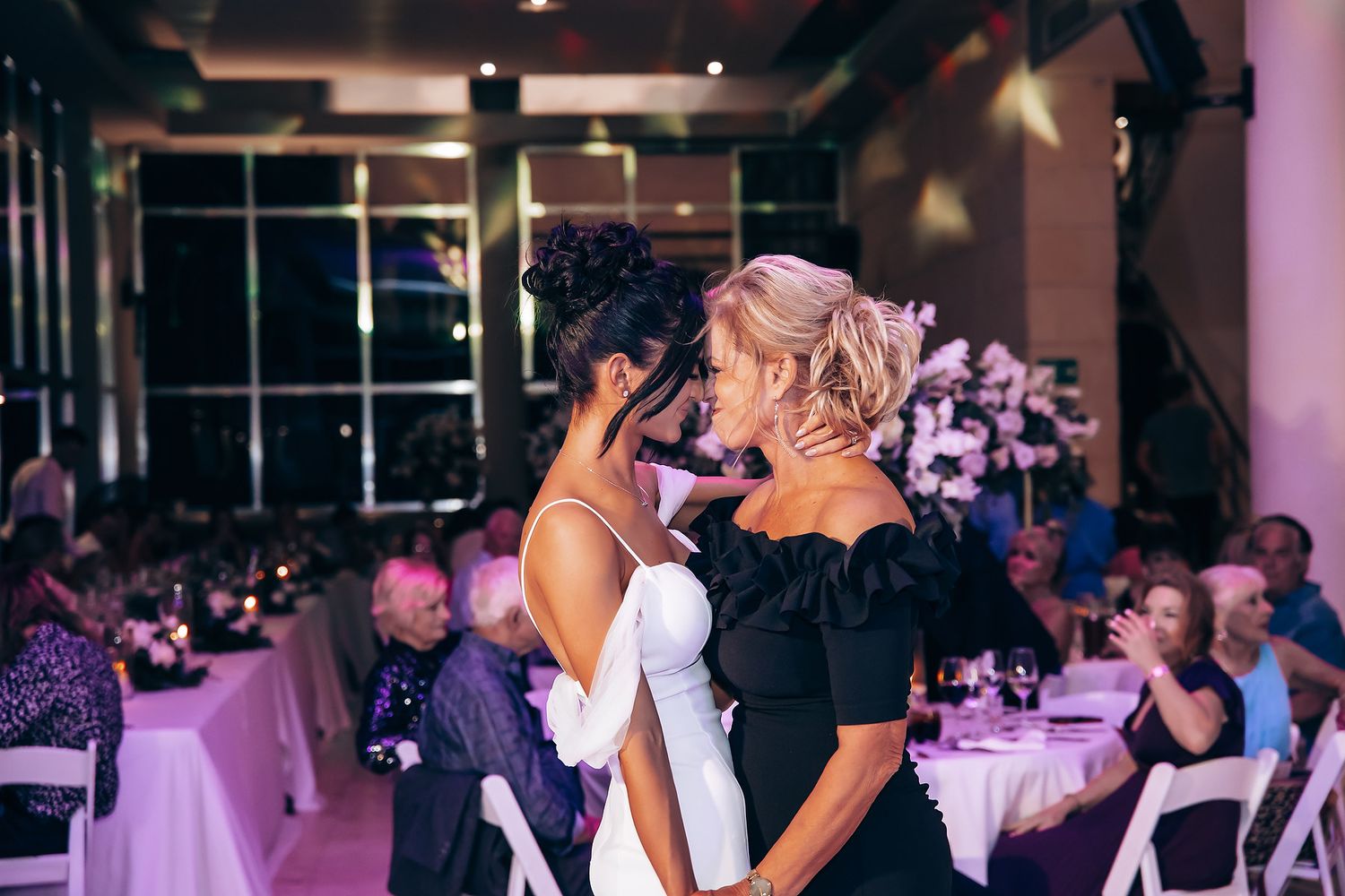 Wedding reception dance floor with purple mood lighting and celebrating guests.