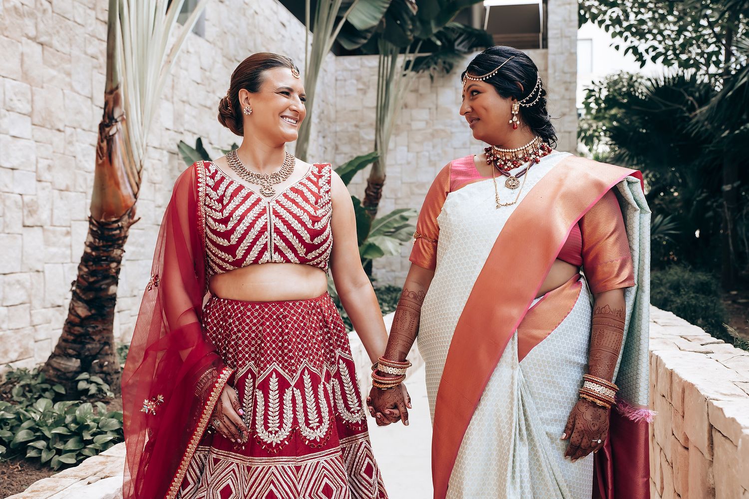Traditional Indian wedding attire featuring red lehenga and white saree outdoors.