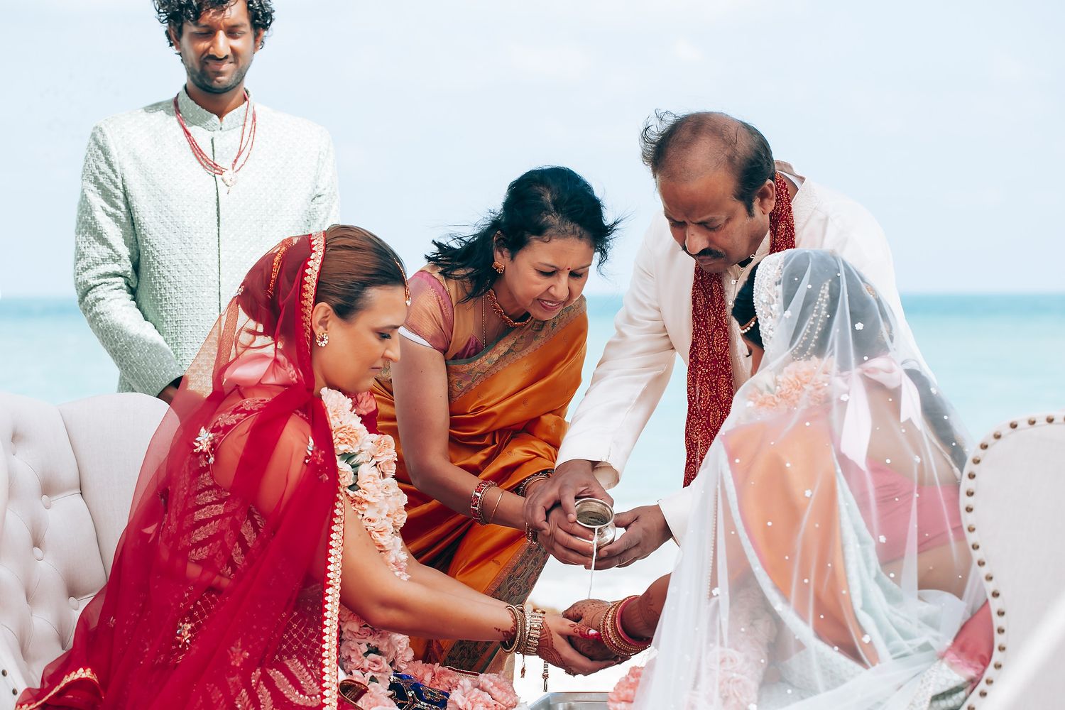 Traditional Indian wedding ceremony with participants performing sacred rituals by the ocean.