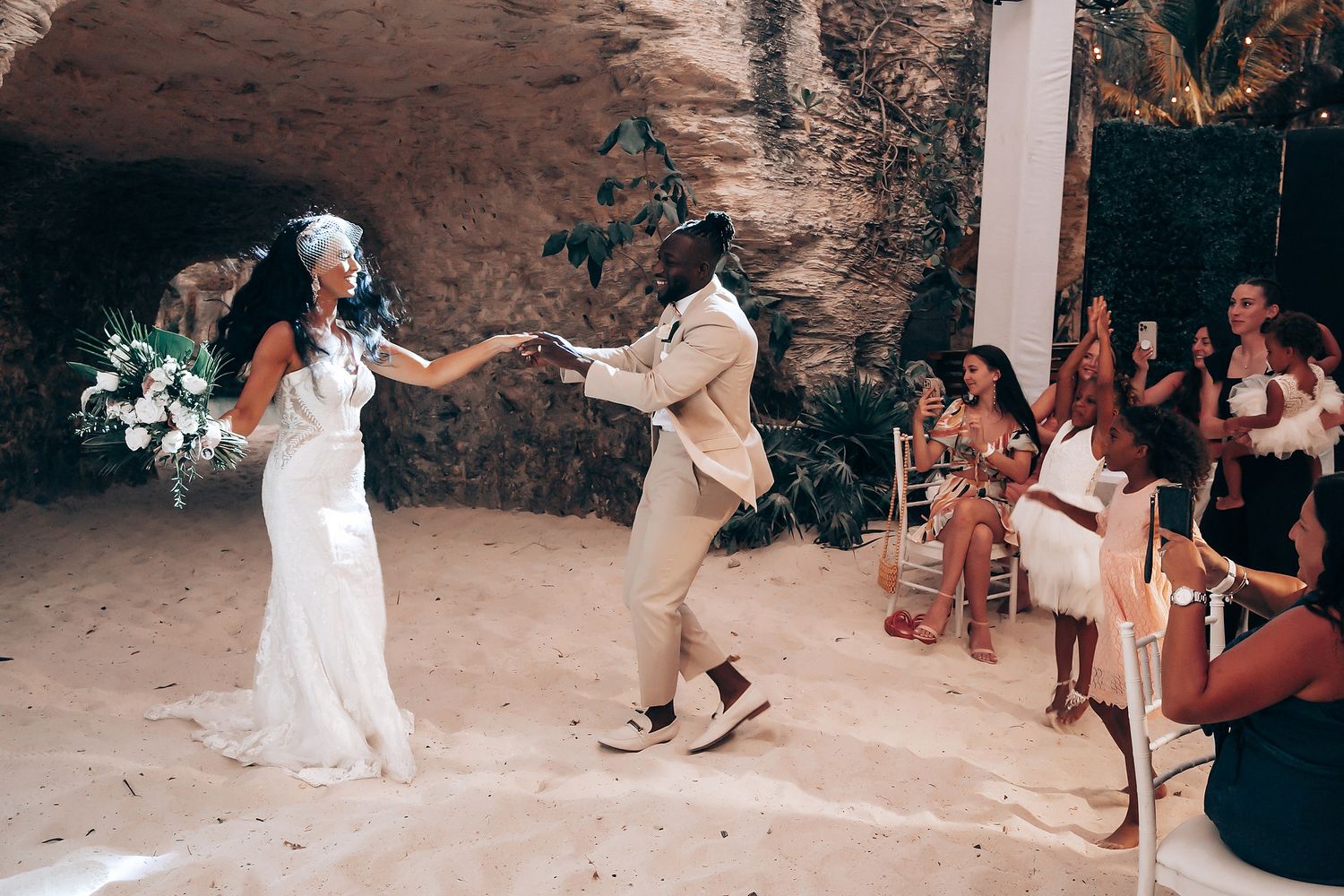 Wedding celebration moment captured in natural cave setting with guests watching.