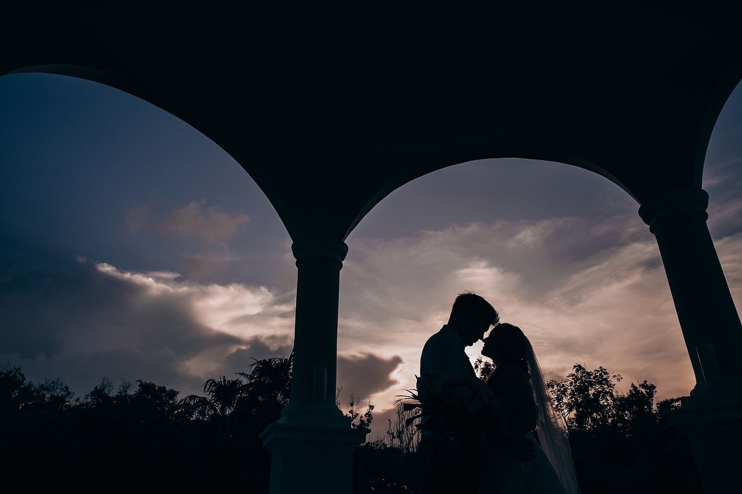 String lights illuminate an outdoor evening wedding reception with silhouetted guests dancing under the night sky.