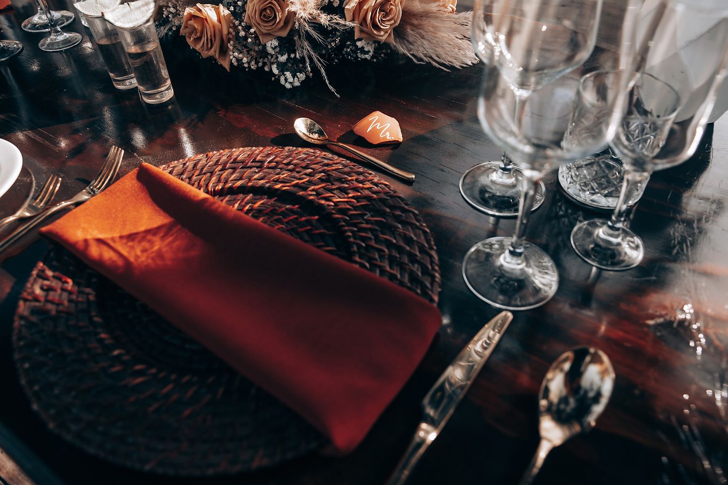 Moody table setting with wine glasses and dark romantic lighting for an elegant event.
