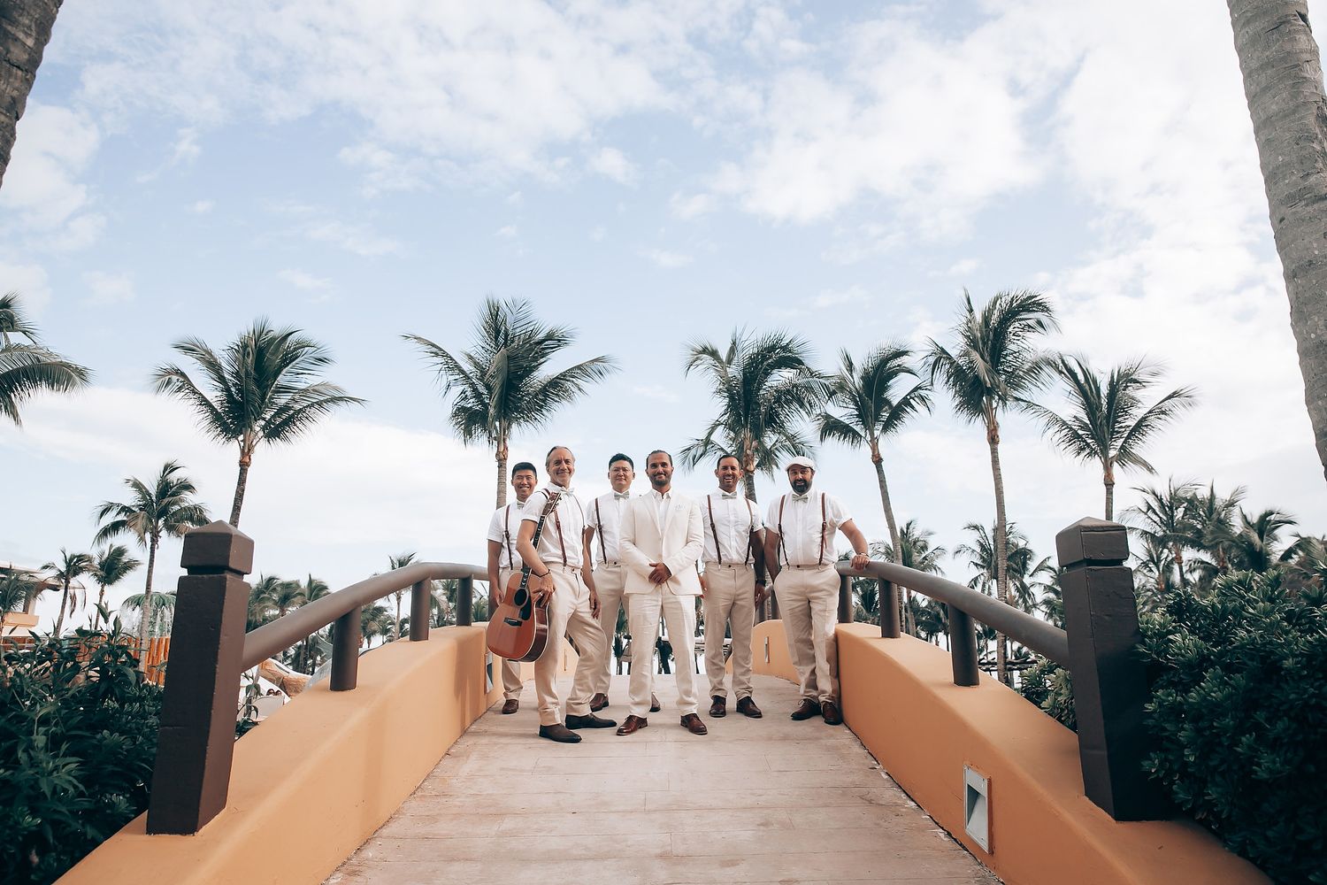 Panoramic view of a beach wedding setup with palm trees and white chairs arranged on sandy shore.