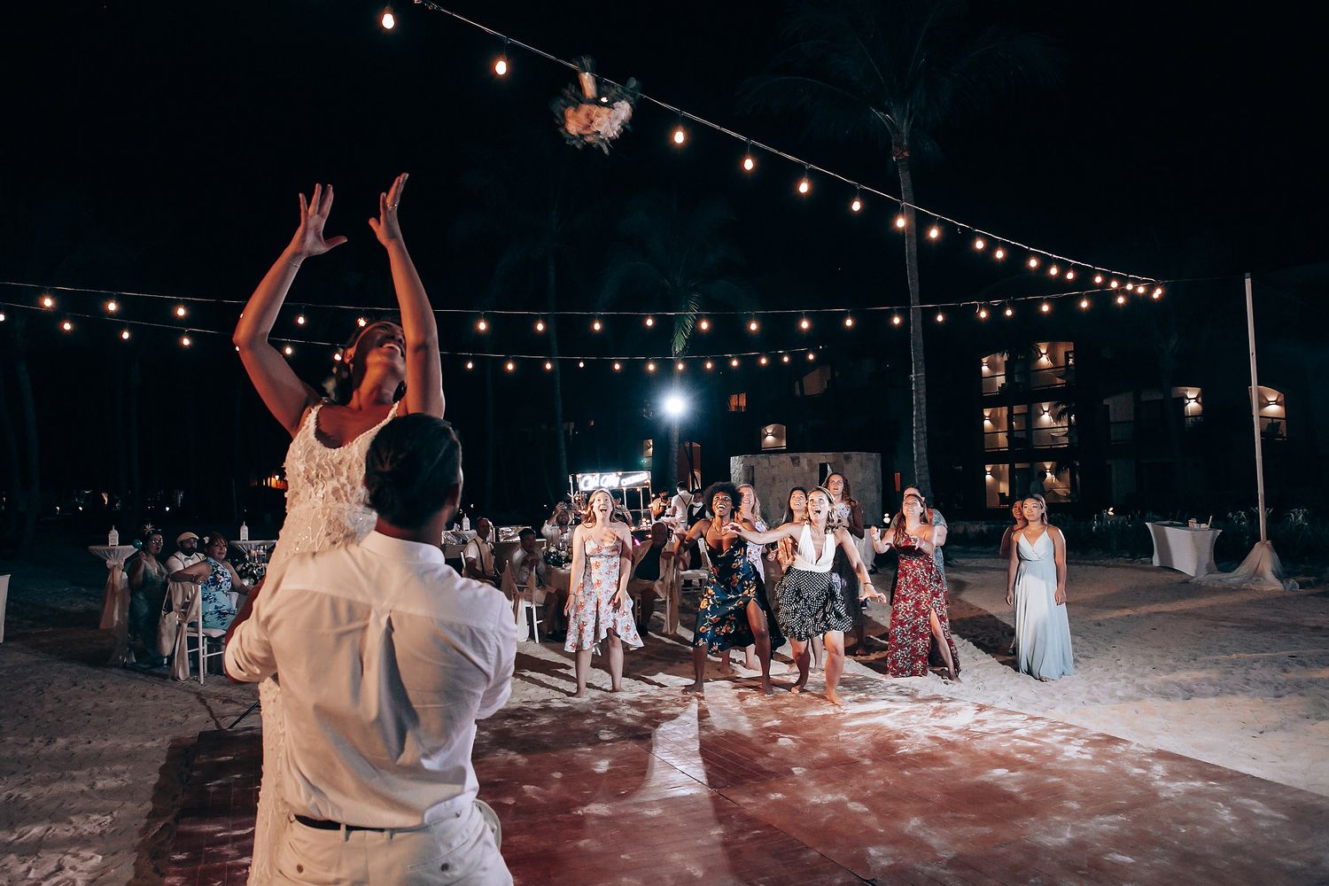 String lights illuminate a nighttime beach wedding reception.