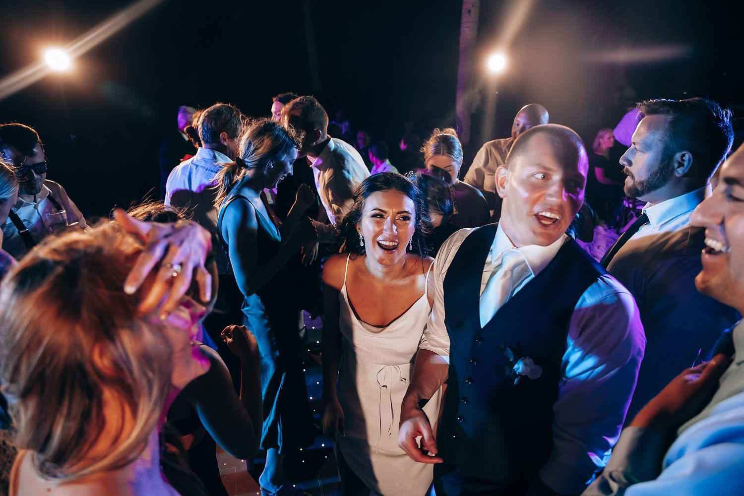 Nighttime wedding reception dance floor filled with guests enjoying the celebration.