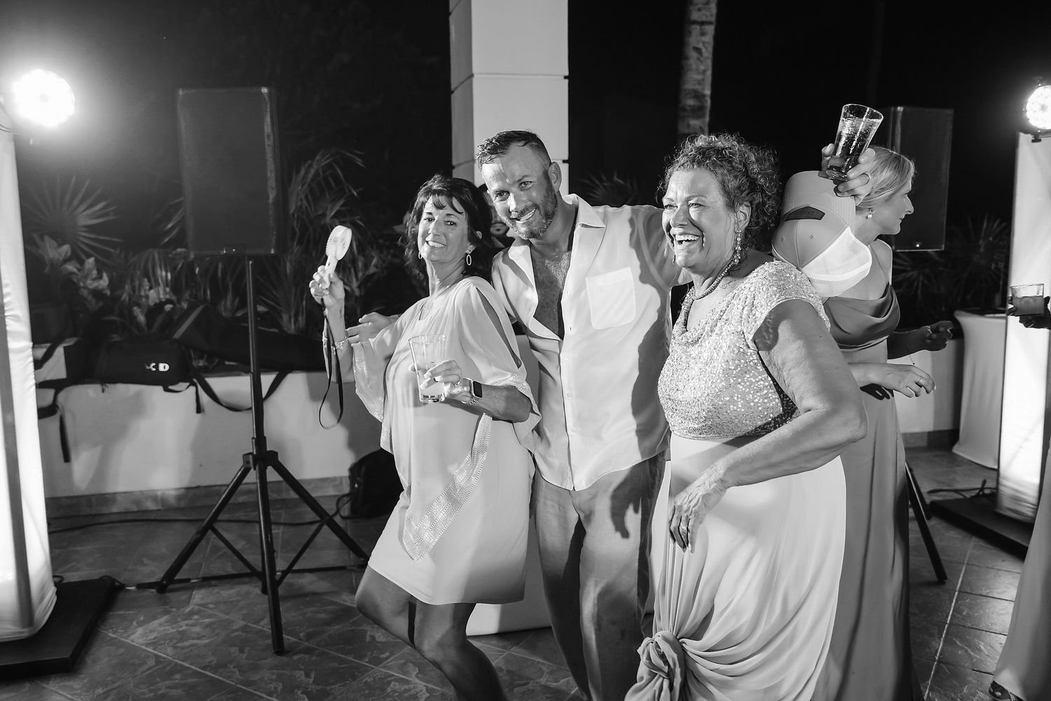 A group of people, presumably wedding guests, celebrating and dancing at a reception.