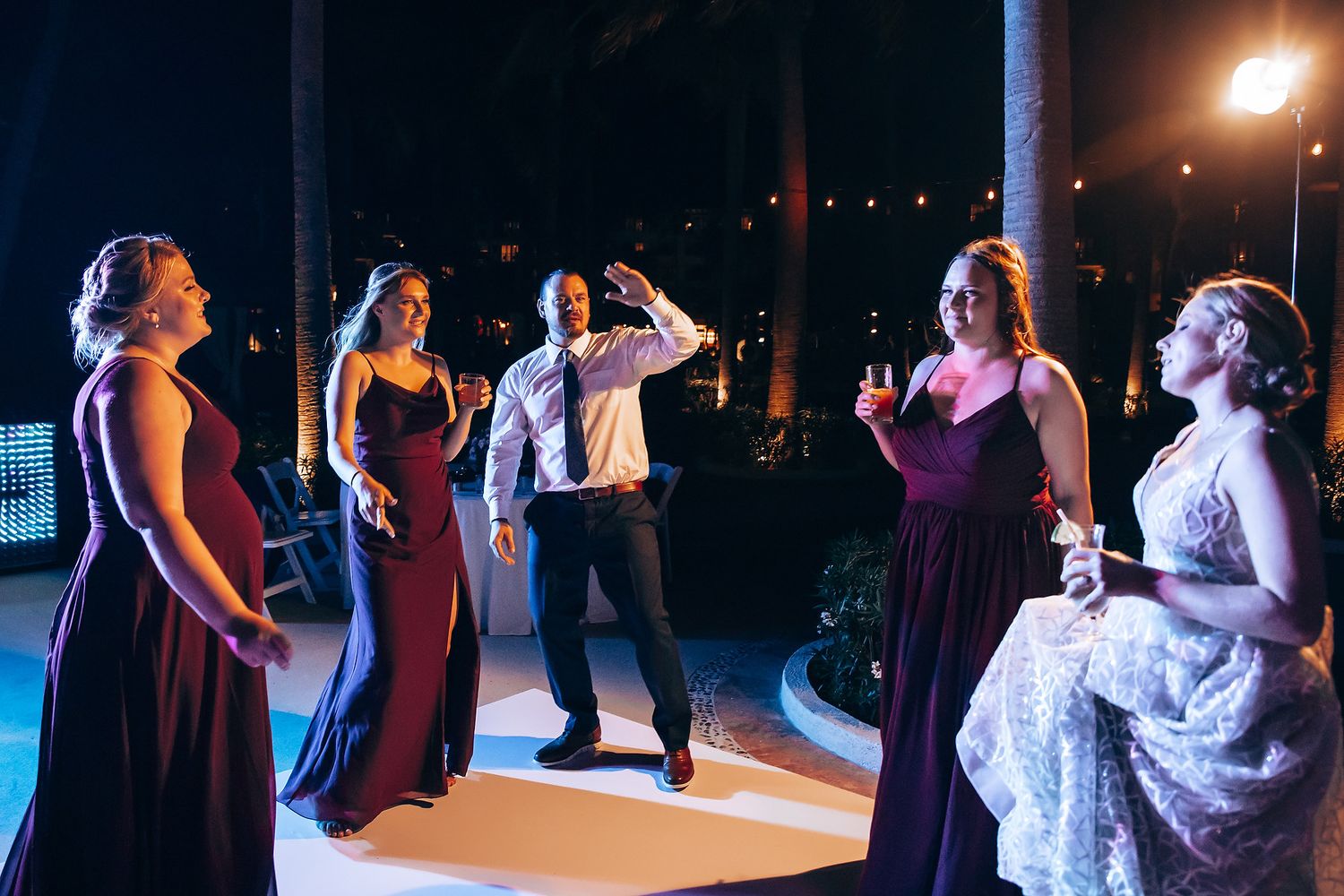 A group of people in formal attire socializing at a nighttime event.