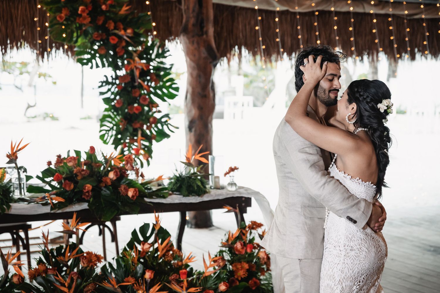 Couple shares first dance surrounded by tropical orange floral arrangements at reception.