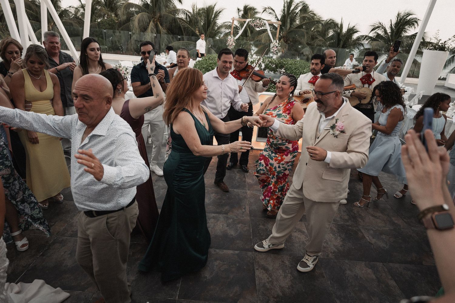Wedding guests dance and celebrate joyfully on an outdoor terrace during a lively wedding reception.