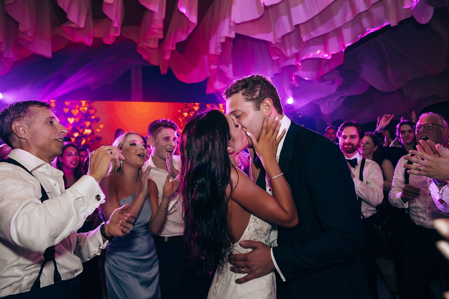 Wedding reception dance party with vibrant purple lighting and decorative elements.