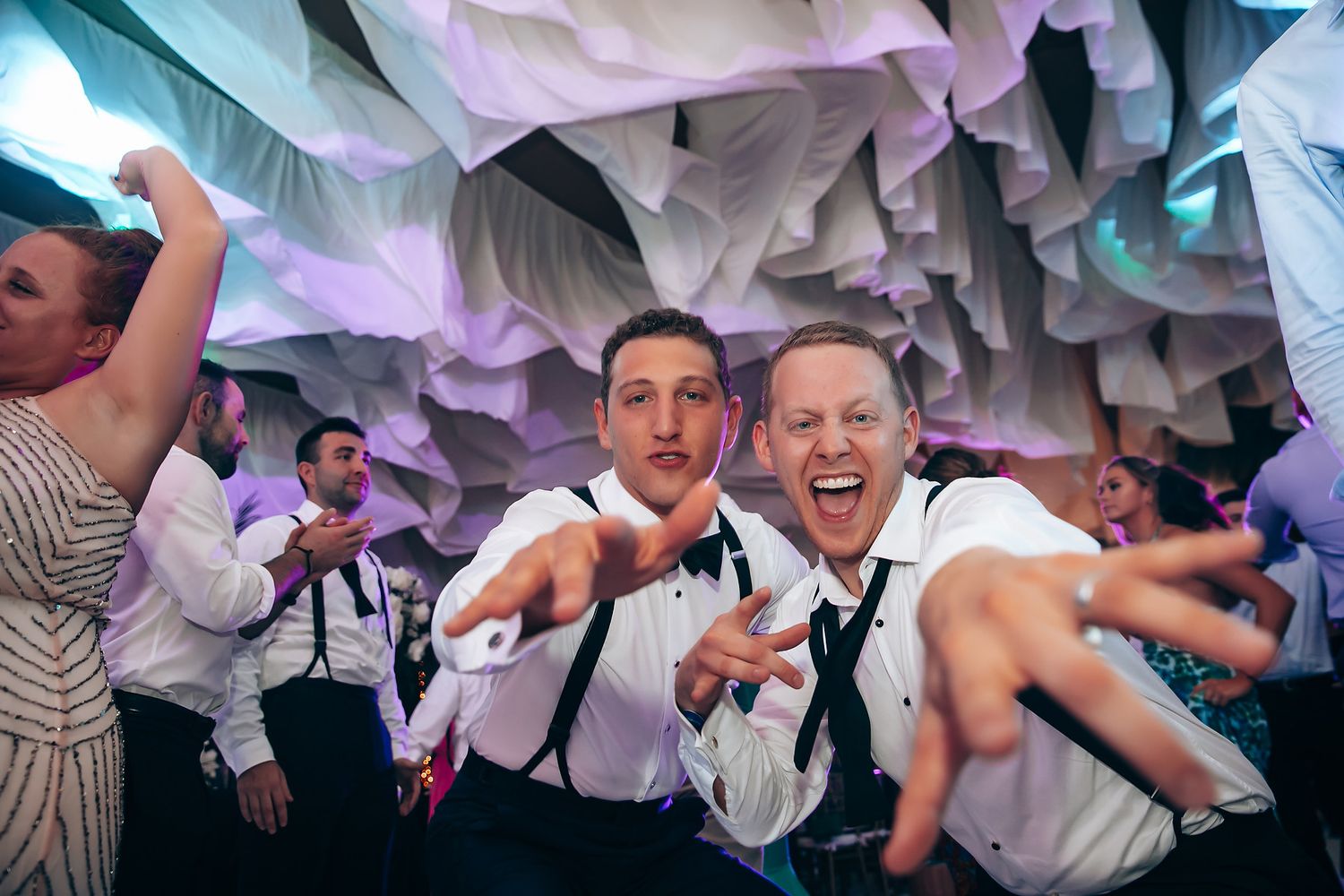 Wedding reception party with guests dancing under dramatic white fabric ceiling installations.