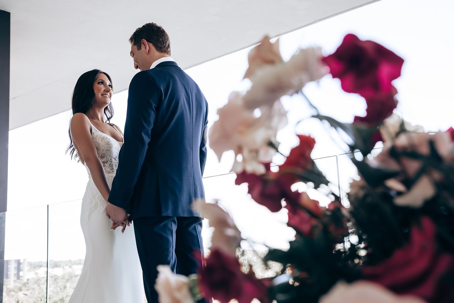 Romantic wedding ceremony with deep red floral arrangements and soft lighting.