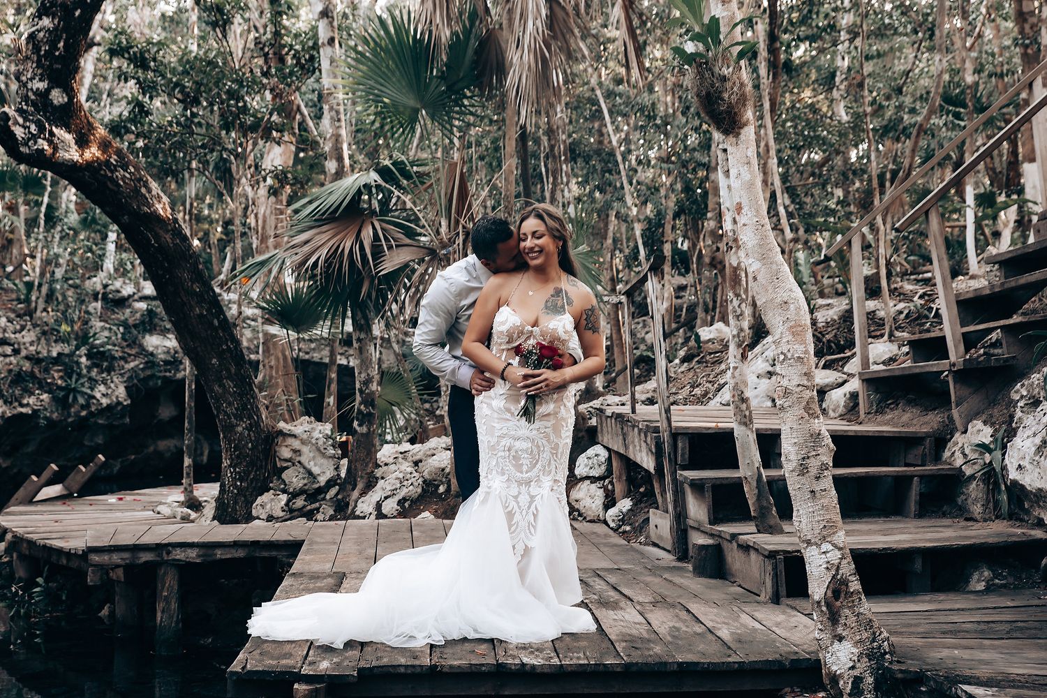 A romantic bridal portrait on a wooden deck surrounded by lush tropical forest.