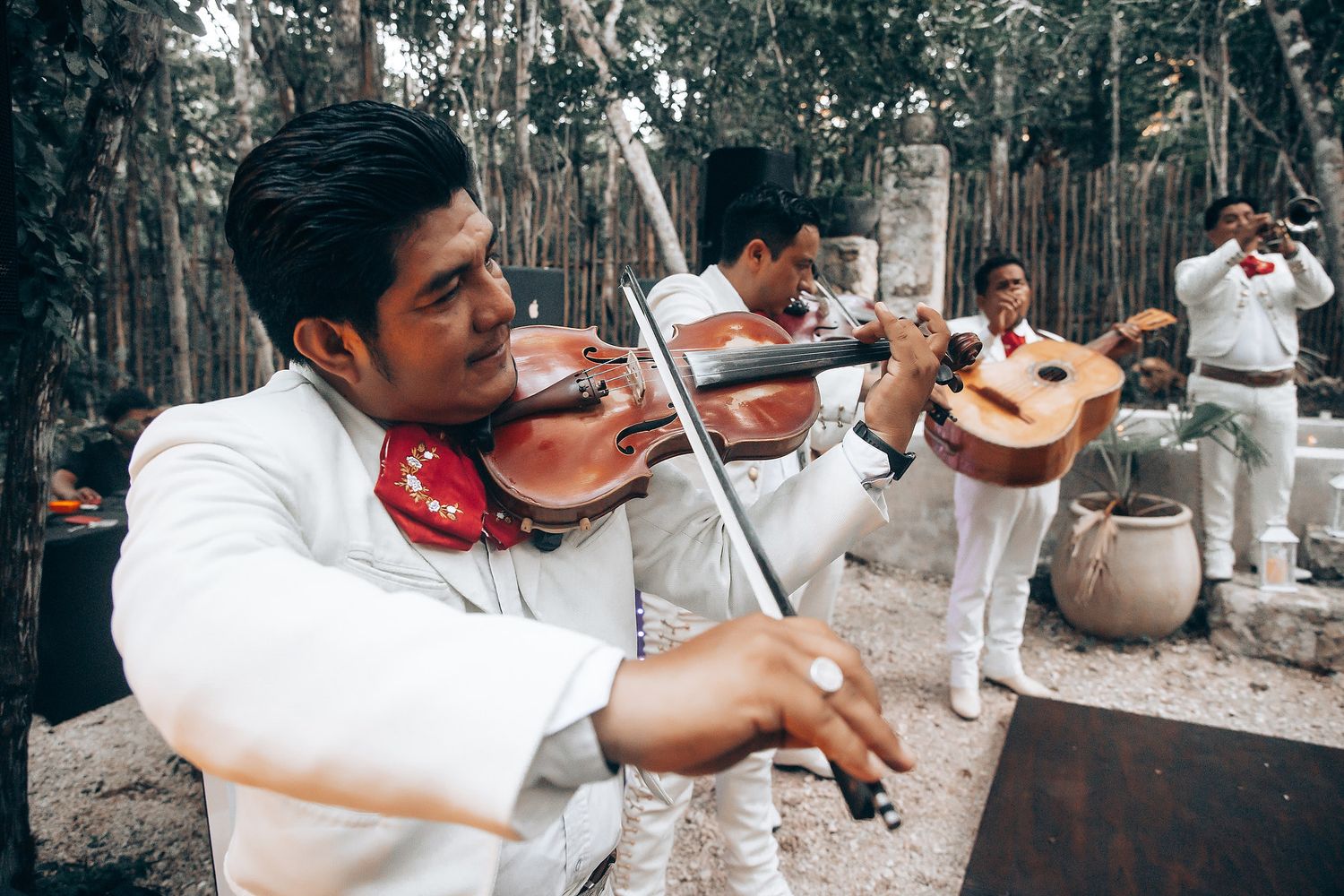 Mariachi violin player performing at outdoor wedding celebration.