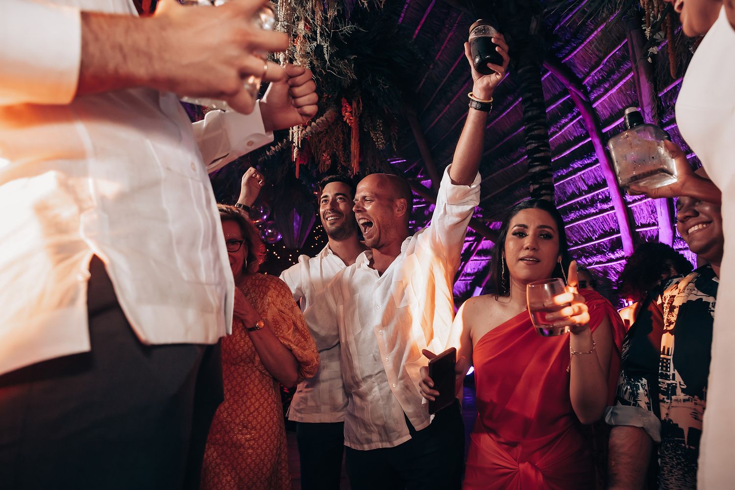 Dance floor filled with celebration and colorful purple lighting at wedding reception party.