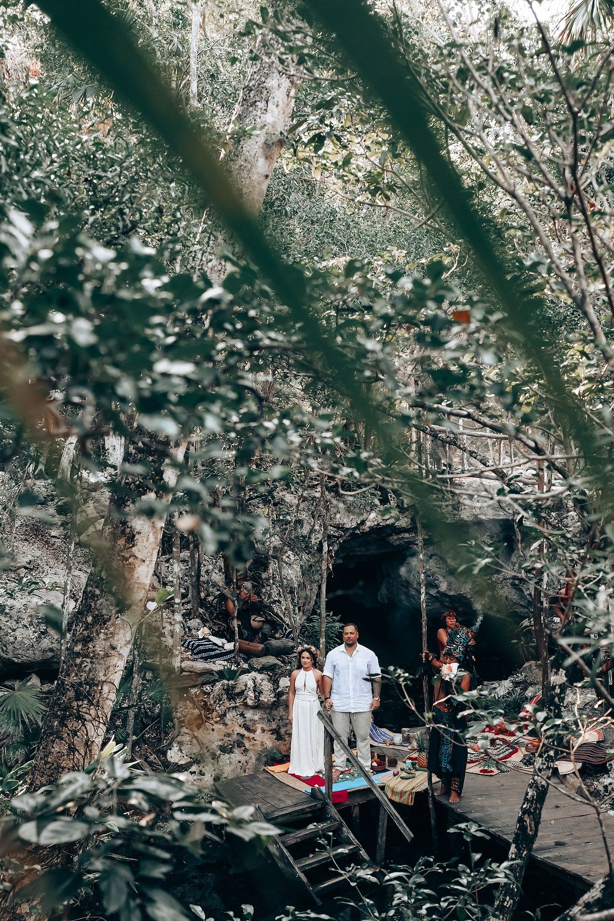 A mystical forest ceremony space is decorated with traditional elements among leafy trees.