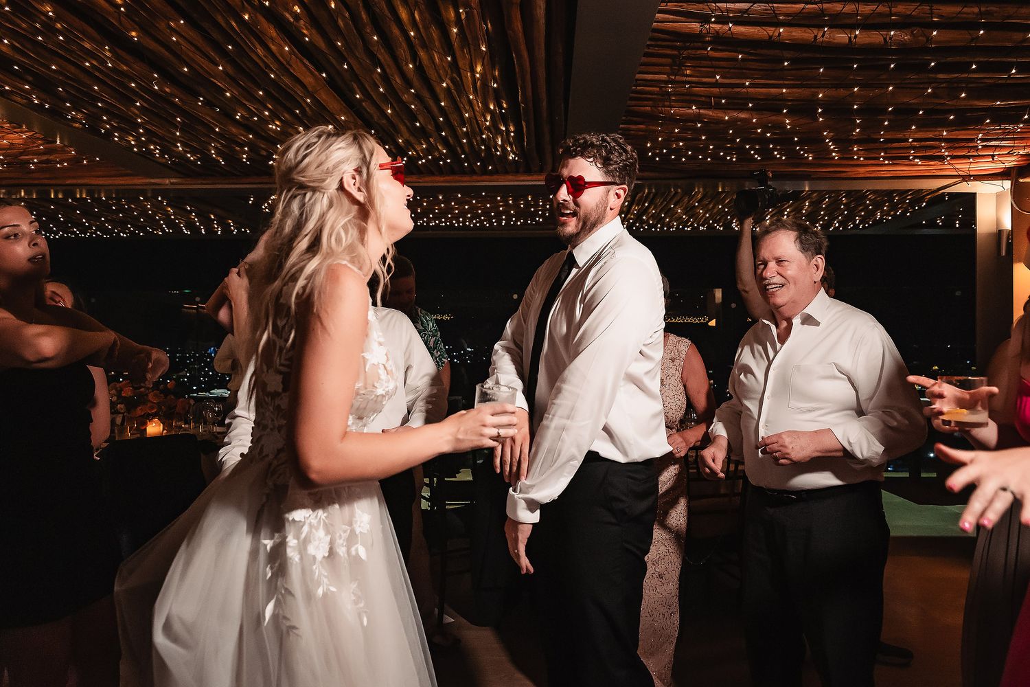 Reception party sequence showing guests dancing under warm lighting and decorative elements.