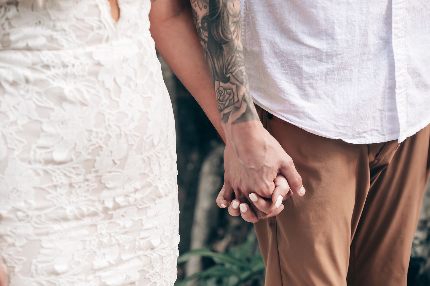 Close-up shot of hands exchanging rings during an outdoor ceremony.
